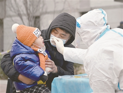 1月9日，在天津市西青区中北镇锦曦花苑社区一处核酸检测点，家长抱着孩子进行核酸检测。新华社记者 李然 摄