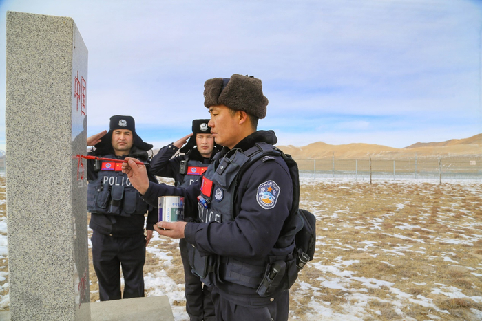 图为民警为界碑描红