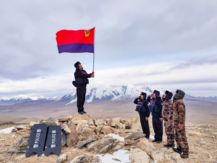 图为民警登顶后向警旗致敬