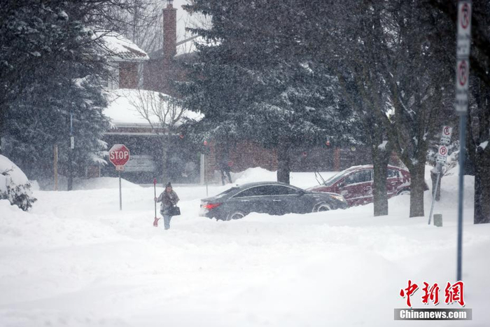 当地时间1月17日，加拿大多伦多，一位手持雪铲的居民行走在积雪的路面上。当日，严重的暴风雪天气席卷加拿大安大略省以及魁北克省的广泛地区，造成多地交通、市政服务等受到影响。 中新社记者 余瑞冬 摄
