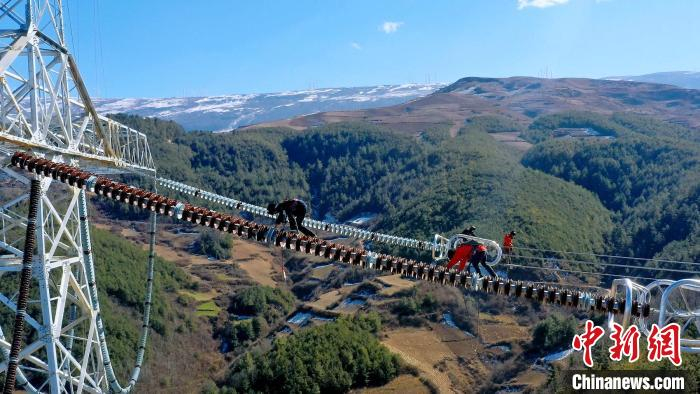 电力工人正在进行高空安装间隔棒。　谭谢阳 摄