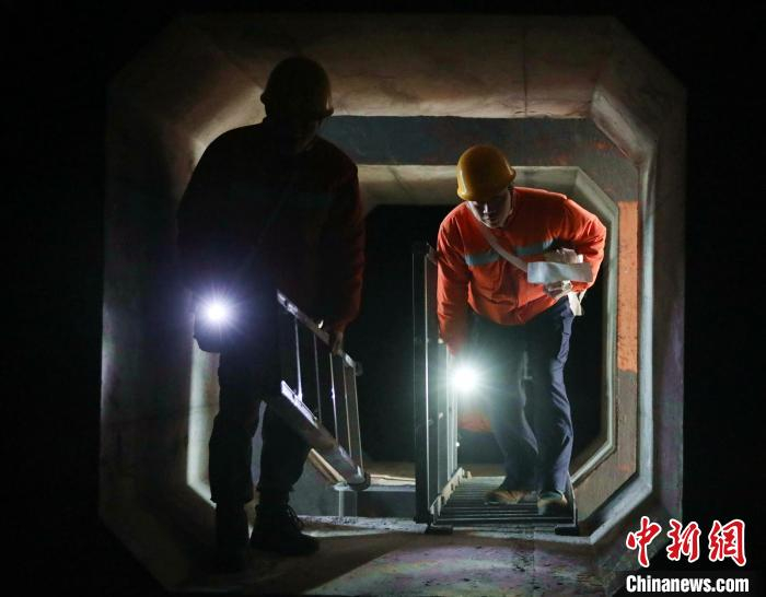 郑华和同事弯腰通过在大桥箱梁连接通道。　易威 摄