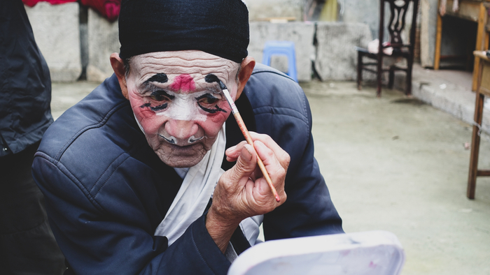 正使用油彩化妆的大南坡村民，同时也是怀梆剧团的成员