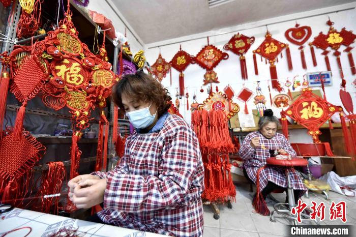 加工车间内，工人们在编织中国结饰品。　赵玉国 摄