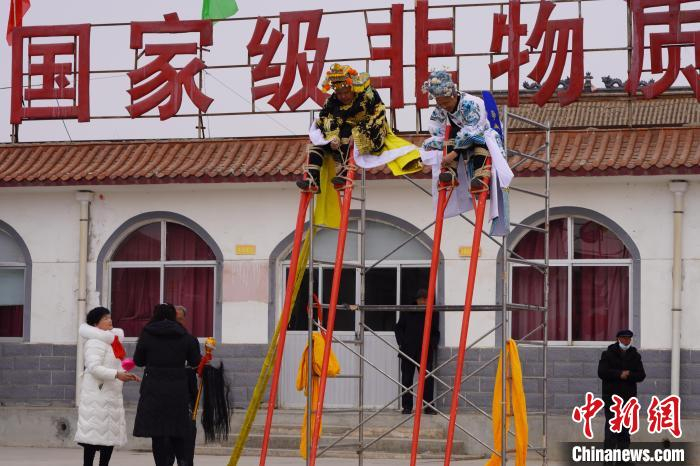 图为表演者正在绑高高跷跷腿准备表演。　九美旦增 摄
