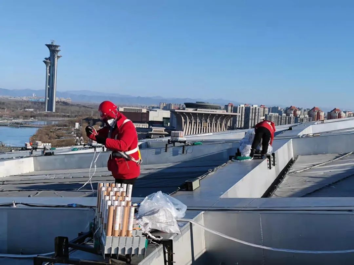 ▲2月20日，相关人员正在“鸟巢”顶上进行焰火的安装。受访者供图