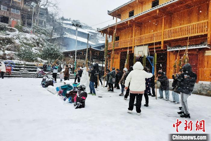 苗族民族在雪人旁载歌载舞。　梁强 摄