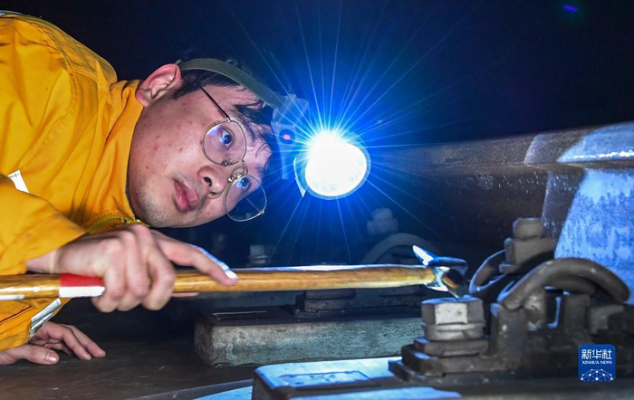  广西沿海铁路公司钦州工务段工作人员利用检查锤探查轨道扣件状态。新华社记者 曹祎铭 摄