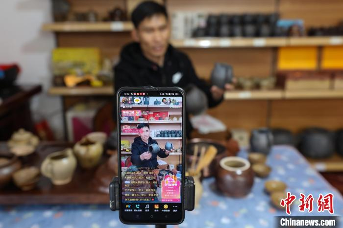 3月4日，廖亮清在通过手机直播讲解“威宁砂陶”烤茶罐。　瞿宏伦 摄