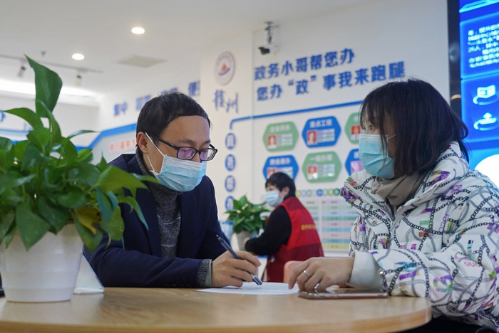 江西省赣州市行政审批局工作人员（左）为办事居民答疑解惑。新华社记者 万象摄