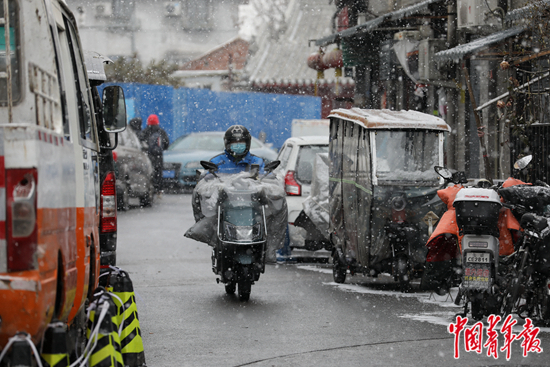  2022年1月20日，北京前门地区的胡同里，外卖员冒雪给客人送餐。据介绍，外卖小哥、快递员等灵活就业新形式在社会中越来越流行，灵活就业人员社会福利偏低、生存压力较大等问题开始凸显，他们的境况也受到社会关注。中青报·中青网记者&nbsp;李建泉/摄