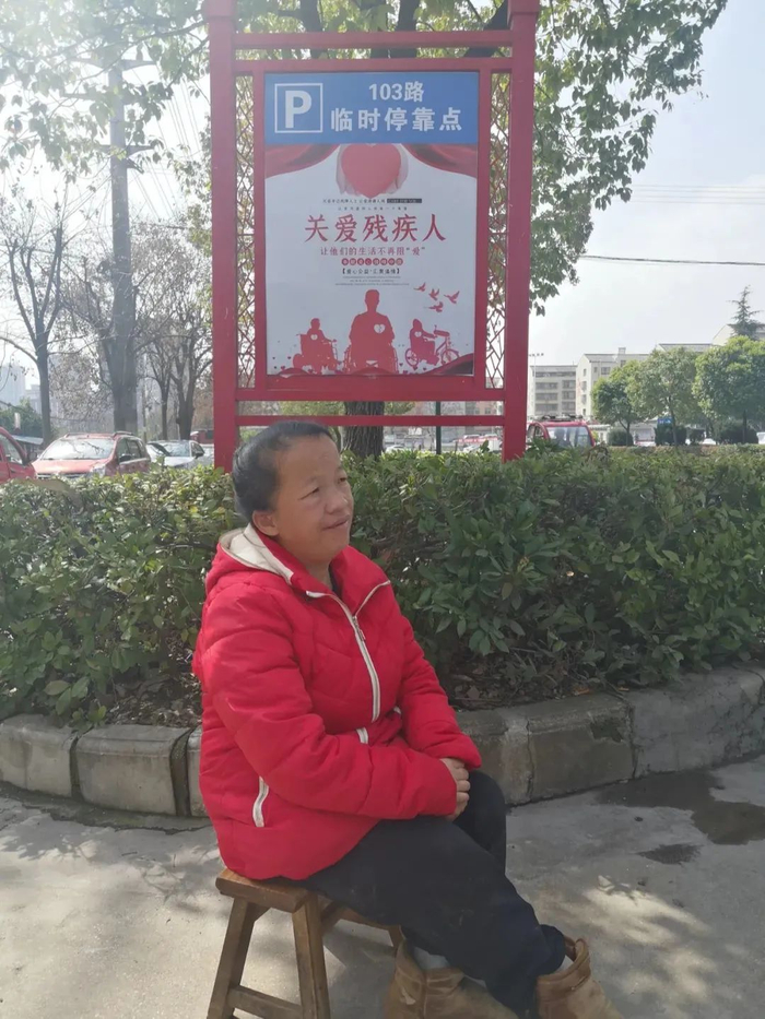 ▲陈新平坐在临时停靠点等车，从医院门口到站点，她只需要走不到五分钟。新京报记者李冰洁 摄