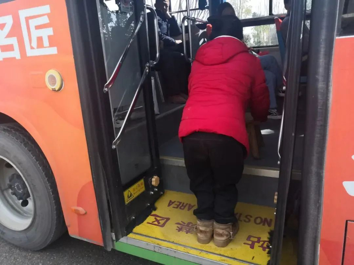 ▲从后门上103路公交车，陈新平需要把板凳放上台阶，用双臂承接整个身体的重量。新京报记者 李冰洁 摄