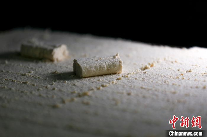 非遗传承人蒋光明将切块的豆腐放在竹条上等待发酵。　施亚磊 摄