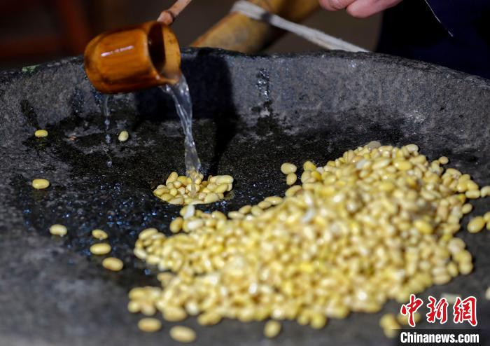 非遗传承人蒋光明将洗净的黄豆放入石碾中研磨。　施亚磊 摄