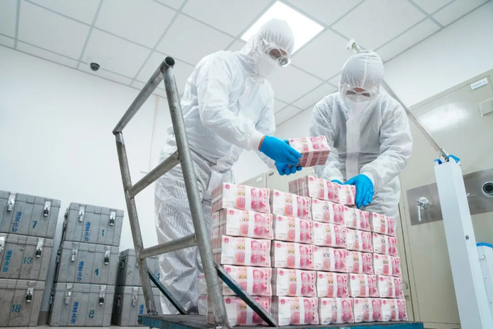 山西一家银行的人民币库房内，工作人员对现金纸币进行消毒作业。视觉中国供图。