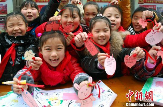 资料图：孩子们开心展示创作的童谣小报和书签。田雯 摄