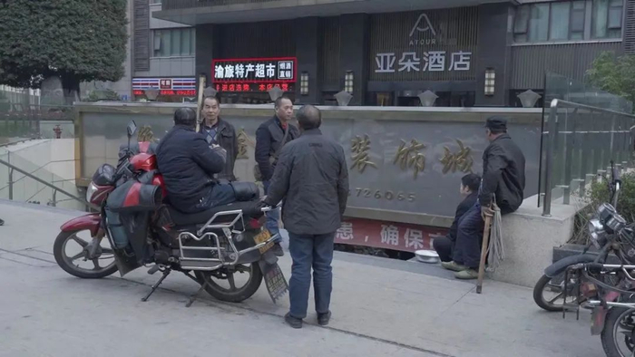 ▲2月28日下午，解放碑附近等待接活的“棒棒”们。新京报记者 戚厚磊 摄