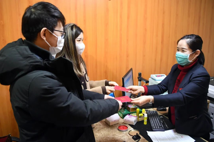 （资料图）北京市海淀区民政局婚姻登记处的工作人员（右）向一对新人颁发结婚证。新华社记者 任超 摄