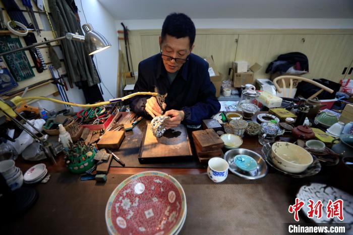 王培波手里拿着金刚钻对瓷器进行打孔。　王磊 摄