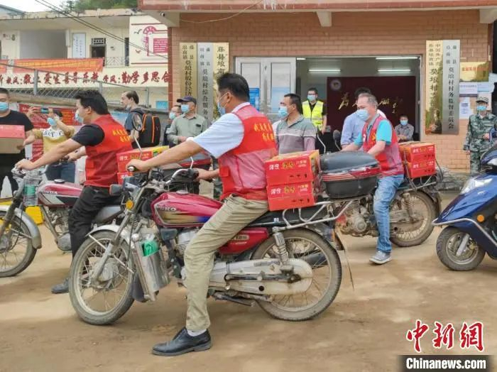 大批村民用摩托车从指挥中心运送救援物资前往客机失事地点。　王以照　摄