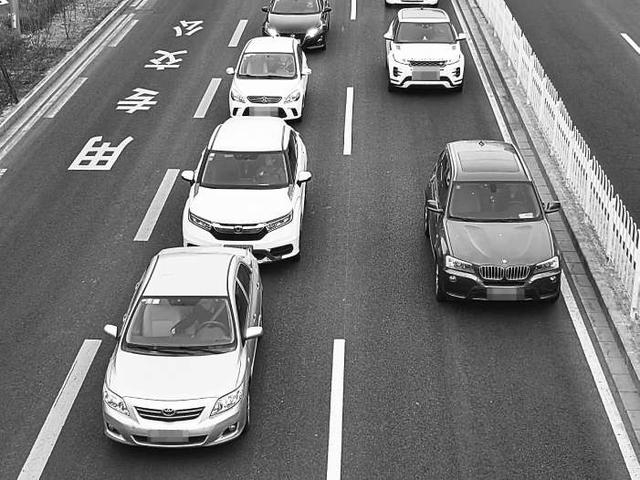 广渠门内大街上，一名司机玩手机被后车催促。