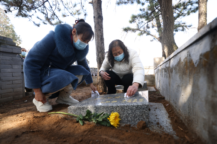 在迁葬仪式上，陈连才烈士的侄女擦拭墓碑。