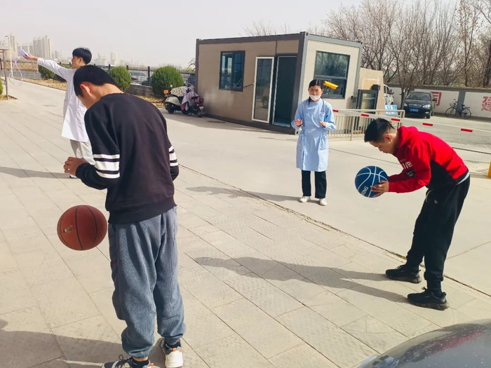 宁夏银川一家残疾人托养服务中心内，几名残疾人在护理人员陪同下学习打篮球 冷瑞洁/摄