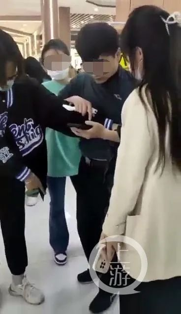 多名学生抓着一青年男子不放，要求其删除手机内的偷拍视频。/视频截图