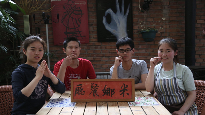 米娜餐厅里，手语是第一语言，听障员工用手语表达出餐厅名称。受访者供图