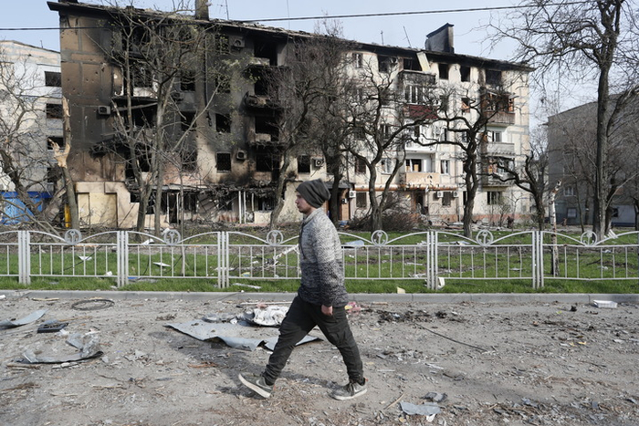 4月17日，在马里乌波尔，当地居民走过被损坏的建筑。新华社发（维克托摄）