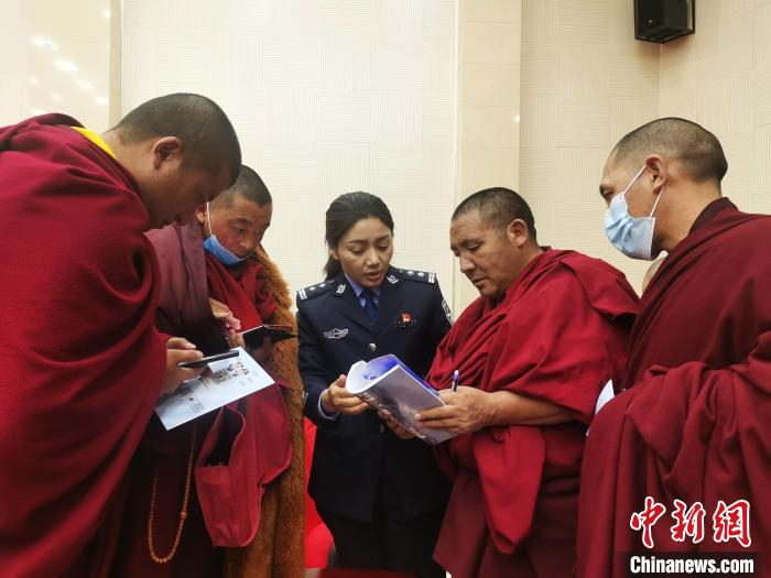 图为反诈民警向僧人学员发放资料并讲解反诈知识。　西藏佛学院供图