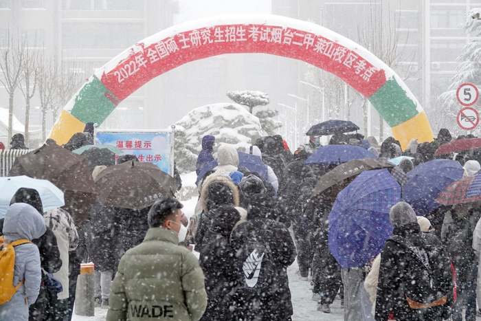  2021年12月25日，山东烟台，参加研究生考试的考生们顶风冒雪进入山东烟台二中莱山校区考点&nbsp; 图源：视觉中国
