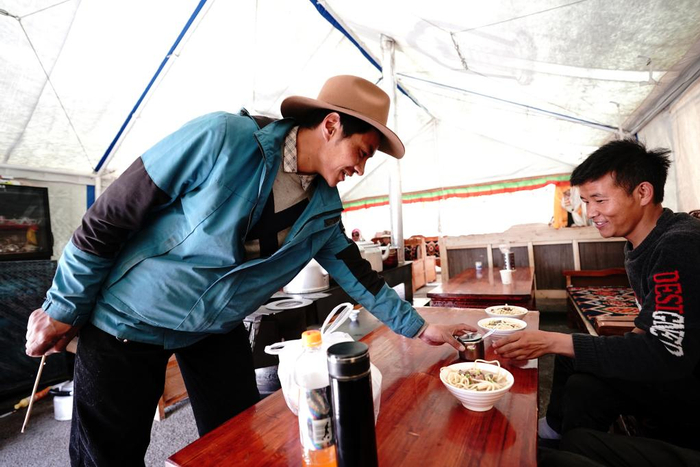 　　在森布日村，村民在甜茶馆里吃藏面（资料图）。新华社记者詹彦摄