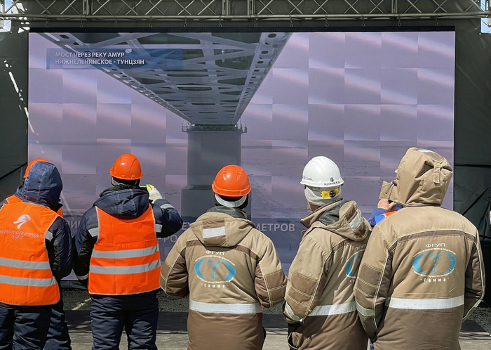 当地时间2022年4月27日，工人们在大屏幕前观看大桥通车。