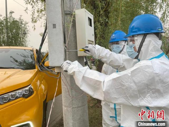 图为国网北京房山供电公司窦店供电所一线运维人员在窦店小高舍村为新增防疫检查站紧急接电。 国网北京电力供图