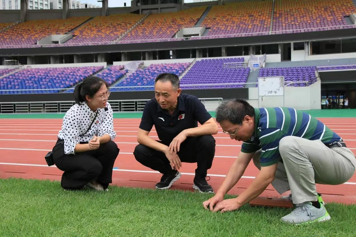 周萌（左一）向体育局领导介绍足球场锚固草坪系统。受访者供图