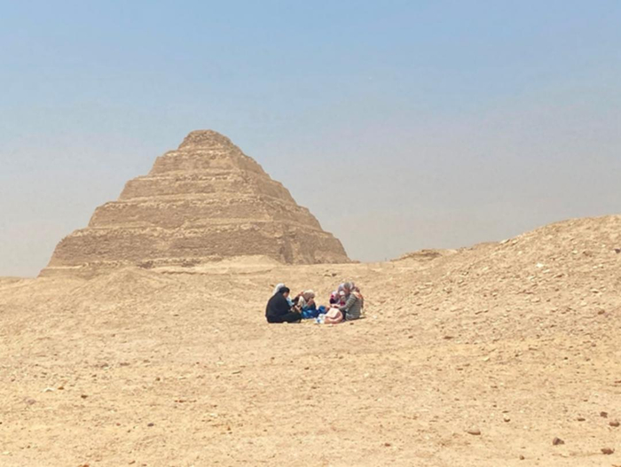 在埃及阶梯金字塔前郊游野餐的当地女性。