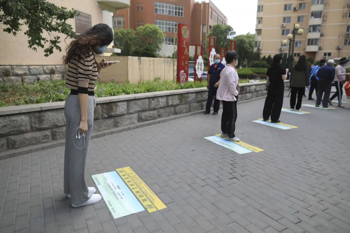 ▲5月5日，海淀区羊坊店街道莲花小区，一位女士在排队时拍摄地上的古诗。&nbsp; 新京报记者 浦峰 摄