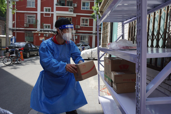 快递员负责将物品送往各个单元楼下的货架上。受访者供图