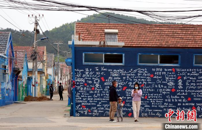 游人行走在满墙漫画的村居间，犹如走进童话世界。　姜汶汶 摄