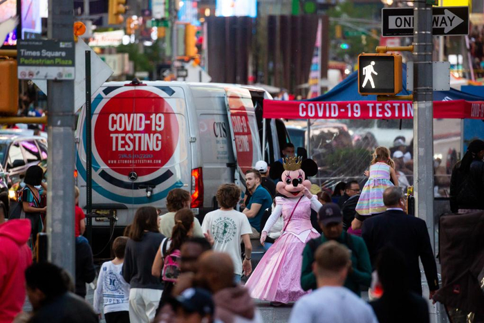 5月12日，在美国纽约时报广场，人们从一个新冠检测点旁经过。新华社发（郭克摄）