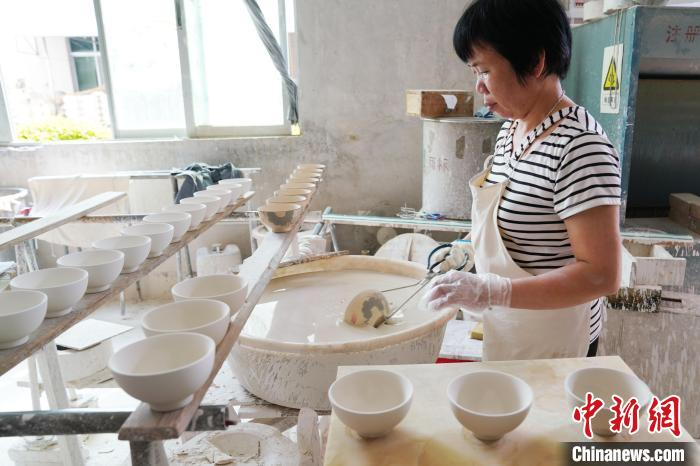 图为手艺人在彩绘后的坯体施一层釉 岳瑞轩 摄