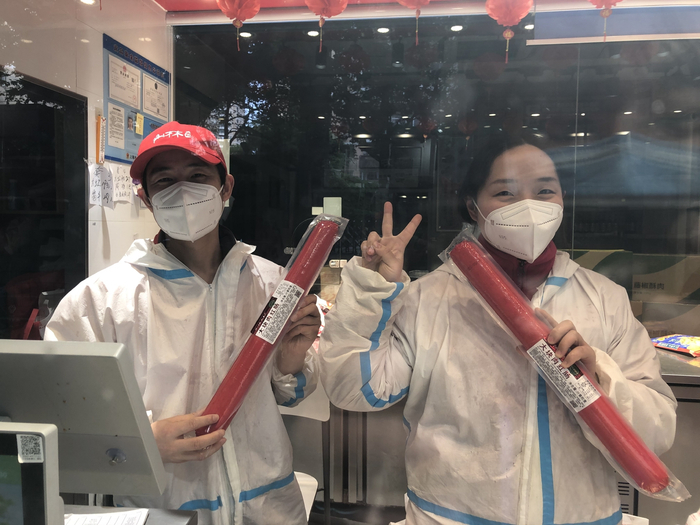 2022年5月18日，上海徐汇，陈林生（左）和同事举着店里的照片食品红肠。本文图片均为澎湃新闻记者李佳蔚 图