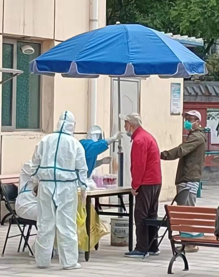 紫东苑小区为特殊人群开通绿色通道，林刚（右一）搀扶着老人优先做核酸检测。  受访者供图