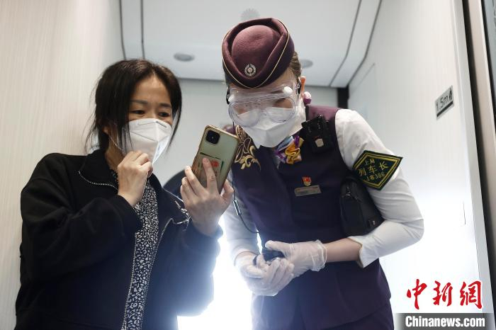 列车长沈乔帮助旅客拨打12306中国铁路服务热线。　殷立勤 摄