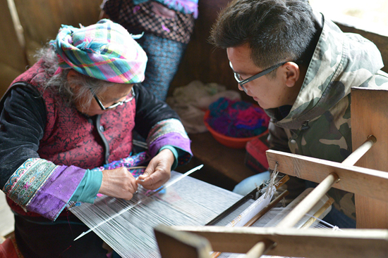     韦旭阳（右）向苗族奶奶学习刺绣技术。受访者供图