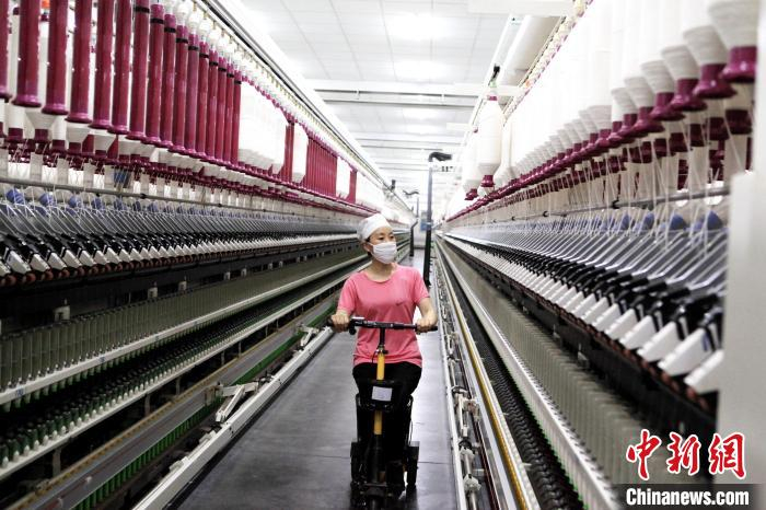 枣阳市万通棉纺实业有限公司智能数字化纺纱车间内，工人骑电动车来回巡查 郭振兴 摄