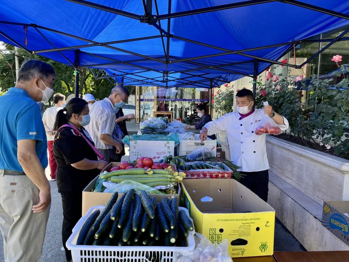 ▲5月25日清晨，大鸭梨石佛营店的蔬菜摊，刘勇（右一）和同事正在忙活。新京报记者 吴淋姝 摄