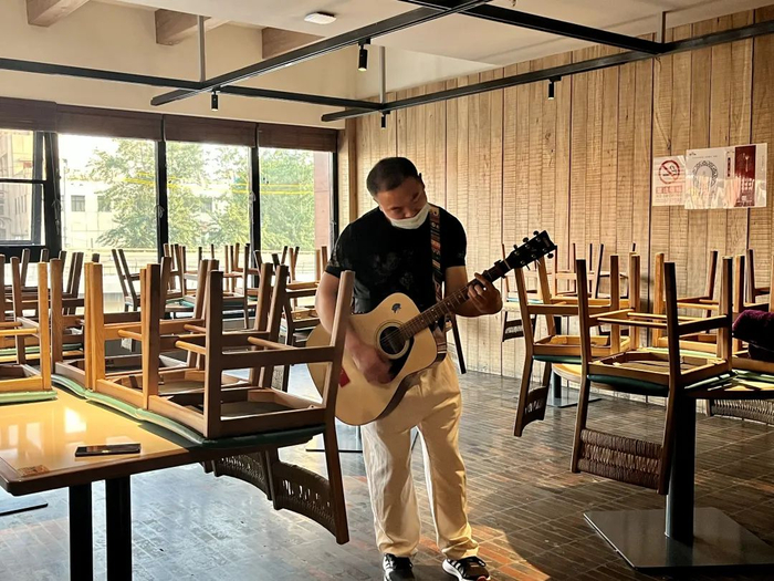 ▲5月23日傍晚，丰台区万丰路商圈，0776食堂大厅，后厨小徐抱着吉他弹唱《蓝莲花》。新京报记者 吴淋姝 摄